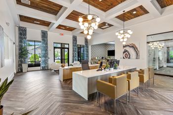 A modern kitchen with a long white island and wooden floors.